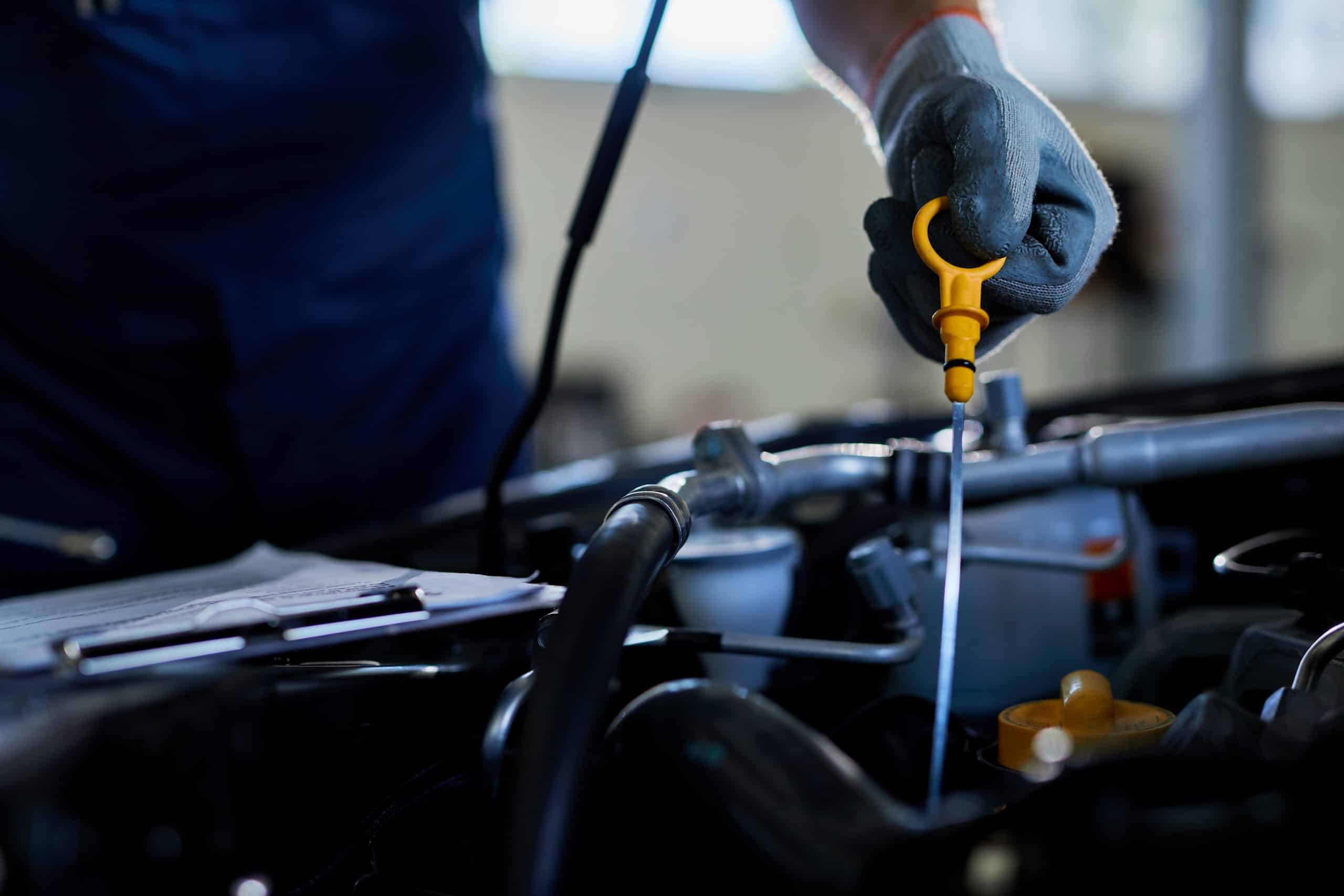 Close-up of a auto repairman checking car oil in a workshop.